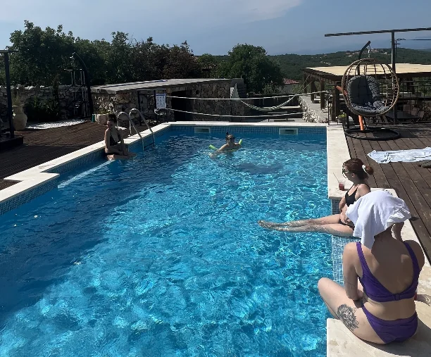 Ljudi opušteni uz bazen i na terasi