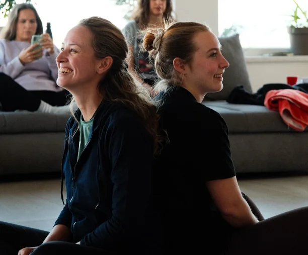 Dvije žene sjede naslonjene leđima jedna na drugu