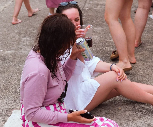 Dvije žene sjede na molu i uživaju u piću tijekom retreat-a.