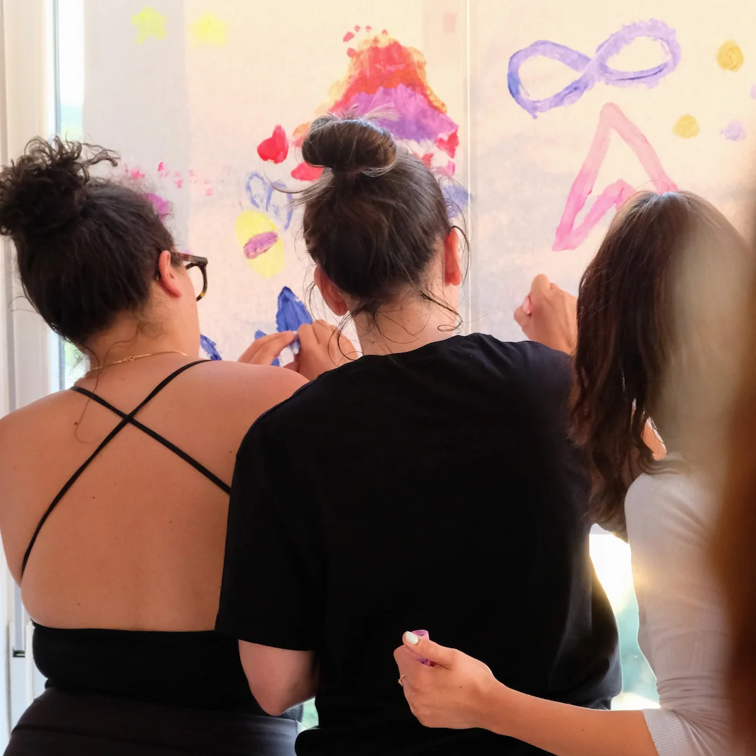 Tri žene okrenute leđima slikaju na papiru s pastelama